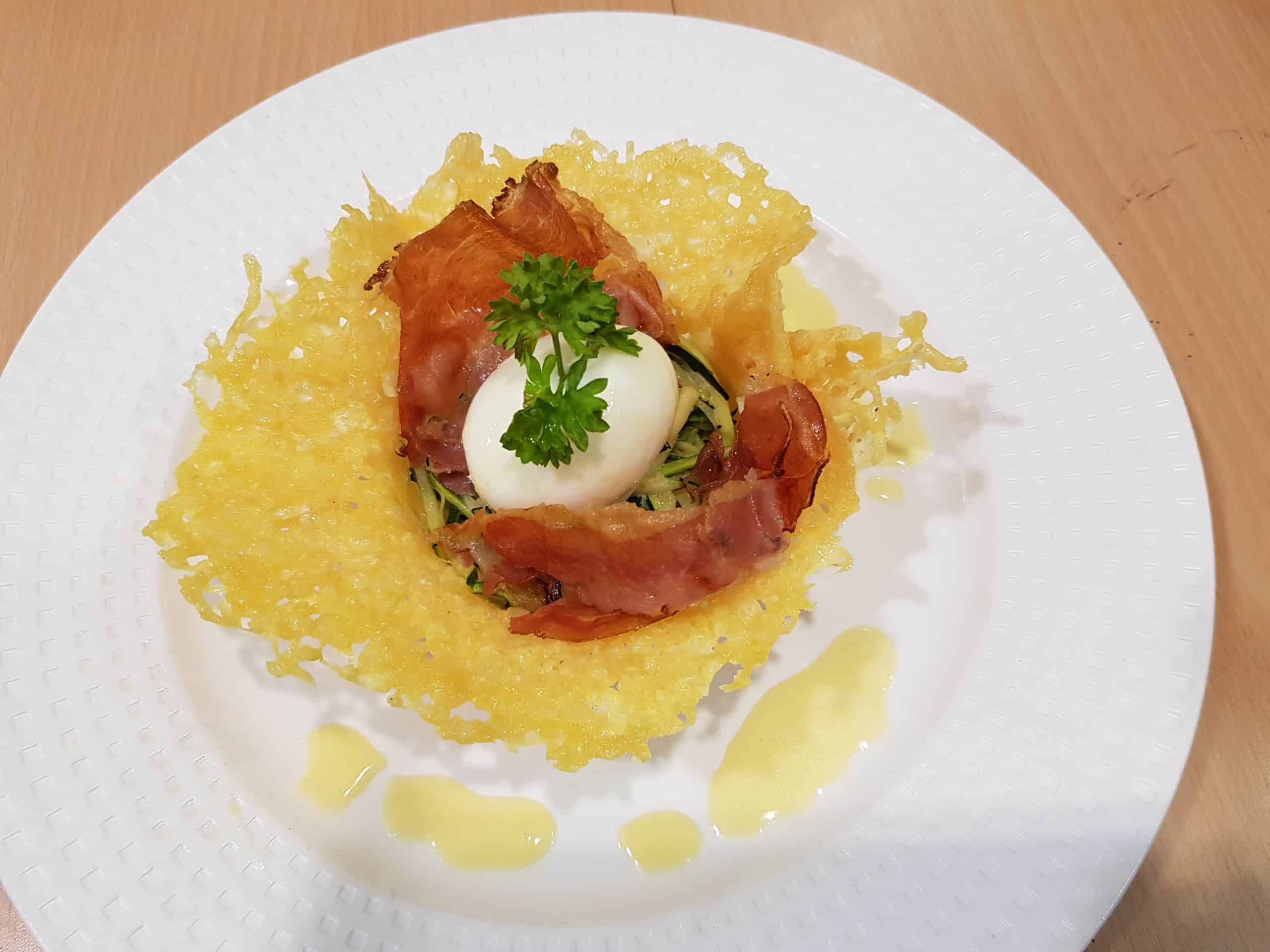 Oeuf mollet et sa corolle de Comté, spaghetti de courgettes et copeaux de jambon de montagne