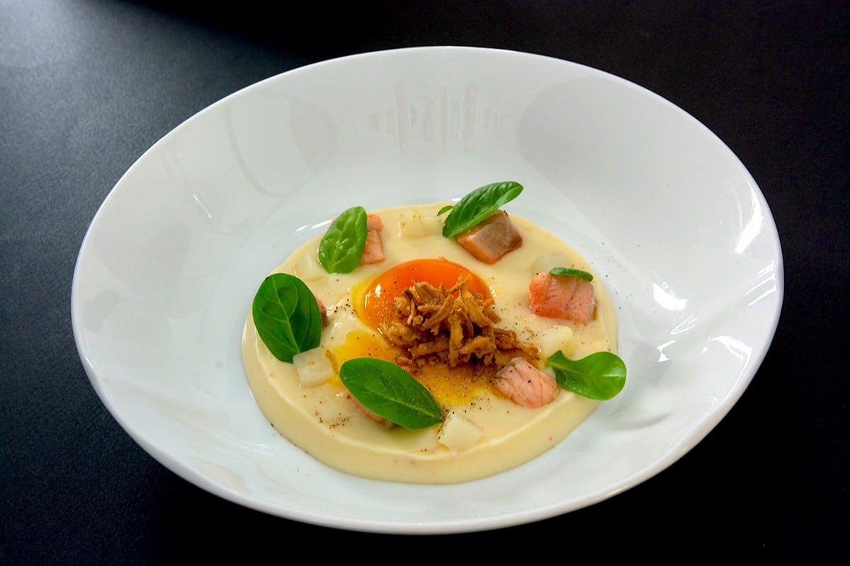 Velours de carottes blanches, jaune d’œuf confit, oignon frit, lardons de saumon frais, brunoise de radis blanc